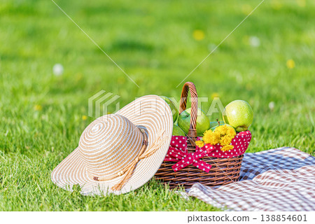 Picnic basket and hat on grass outdoor scene Picnic basket and hat on grass outdoor scene 138854601