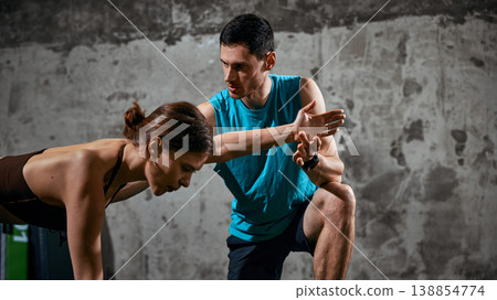 Man coaching woman on exercise technique during gym workout session. Man coaching woman on exercise technique during gym workout session. 138854774