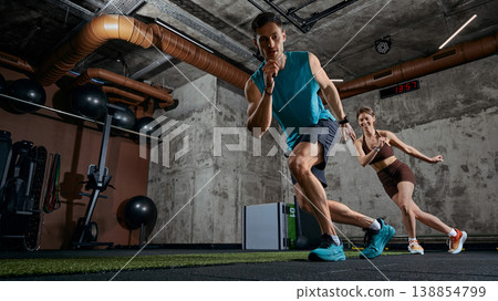 Man and woman performing dynamic shuttle run exercise together in modern gym. Man and woman performing dynamic shuttle run exercise together in modern gym. 138854799