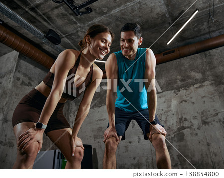 Man and woman resting after workout smiling during gym training session. Man and woman resting after workout smiling during gym training session. 138854800