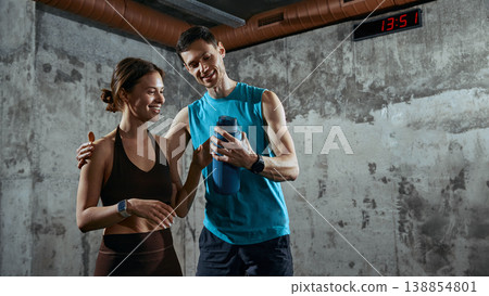 Man showing fitness progress on smartphone to woman after workout session in gym Man showing fitness progress on smartphone to woman after workout session in gym 138854801