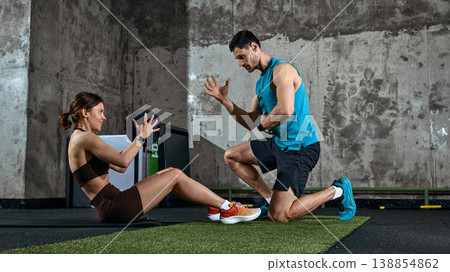 Fitness trainer guiding woman doing sit up exercise with medicine ball in gym. 138854862