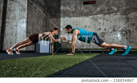 Fitness trainer supervising woman performing plank exercise in modern gym Fitness trainer supervising woman performing plank exercise in modern gym 138854867