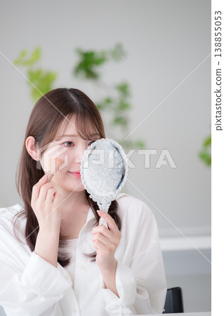 一張特寫鏡頭,一位女士對著手鏡塗抹腮紅,展現了她自然的妝容和美容護理習慣。 一張特寫鏡頭,一位女士對著手鏡塗抹腮紅,展現了她自然的妝容和美容護理習慣。 138855053