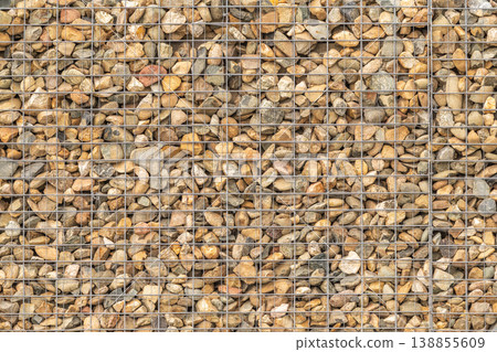 Modern Gabion Wall From Rocks And Stones In Metal Wire Box. Reinforcement and Abutment Protective Construction Modern Gabion Wall From Rocks And Stones In Metal Wire Box. Reinforcement and Abutment Protective Construction 138855609