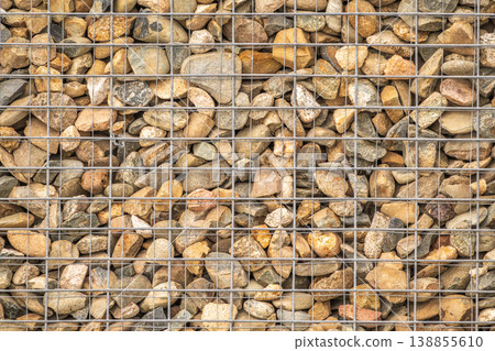 Modern Gabion Wall From Rocks And Stones In Metal Wire Box. Reinforcement and Abutment Protective Construction Modern Gabion Wall From Rocks And Stones In Metal Wire Box. Reinforcement and Abutment Protective Construction 138855610