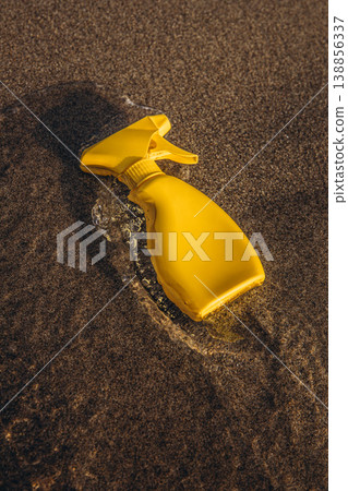 Yellow sunscreen spray bottle lying in shallow sea water on sandy beach Summer sun protection concept minimal product mockup 138856337