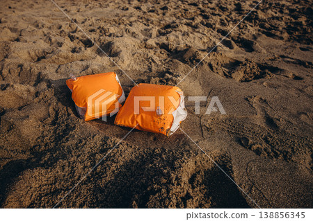 Inflatable armbands on sandy beach Child water safety concept swimming protection and learning basics of safe behavior near sea 138856345
