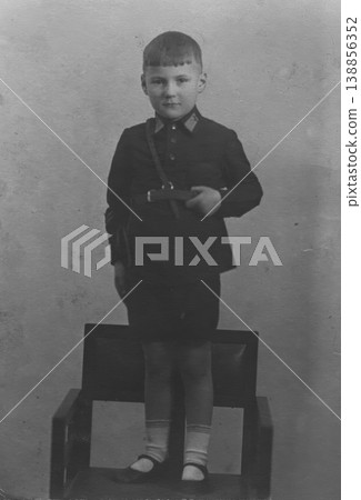 Vintage boy in school uniform standing on chair studio portrait Vintage boy in school uniform standing on chair studio portrait 138856352