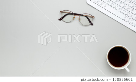 Minimal morning workspace with coffee cup, keyboard, and glasses fostering focused atmosphere 138856661