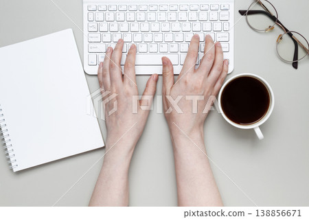 Woman typing on keyboard planning tasks in notebook with coffee supporting focused work Woman typing on keyboard planning tasks in notebook with coffee supporting focused work 138856671