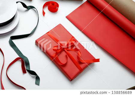 Wrapped gift in red paper tied with satin ribbon for holiday celebration giving Wrapped gift in red paper tied with satin ribbon for holiday celebration giving 138856689