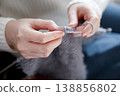 Woman in white sweater knitting with needles creating cozy handmade fabric 138856802