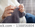 Woman in white sweater knitting with needles creating cozy handmade fabric 138856804