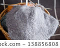 Knitted handmade fabric resting on basket filled with colorful yarn for craft project 138856808
