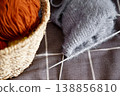 Knitted handmade fabric resting on basket filled with colorful yarn for craft project 138856810