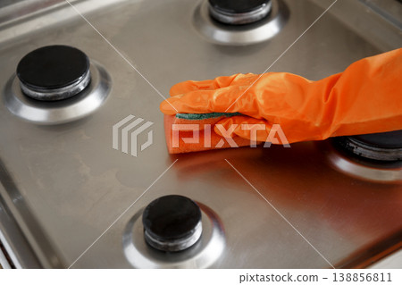 Woman wipes washed clean gas stove with sponge in kitchen 138856811