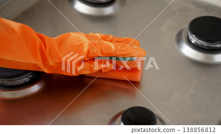 Woman cleaning gas stove with sponge in kitchen after washing 138856812