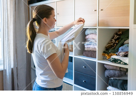 Woman organizing fresh laundry in closet, spring cleaning at home. Woman organizing fresh laundry in closet, spring cleaning at home. 138856949