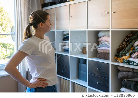 Woman organizing fresh laundry in closet, spring cleaning at home. Woman organizing fresh laundry in closet, spring cleaning at home. 138856960