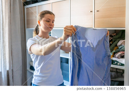 Woman organizing fresh laundry in closet, spring cleaning at home. Woman organizing fresh laundry in closet, spring cleaning at home. 138856965