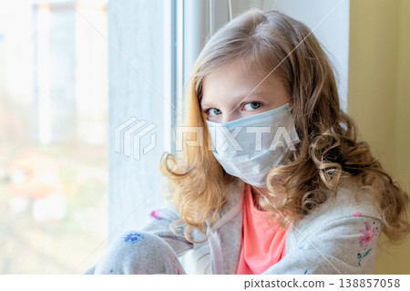 girl in medical mask with teddy bear, looking out the window, quarantine coronavirus. sick children girl in medical mask with teddy bear, looking out the window, quarantine coronavirus. sick children 138857058