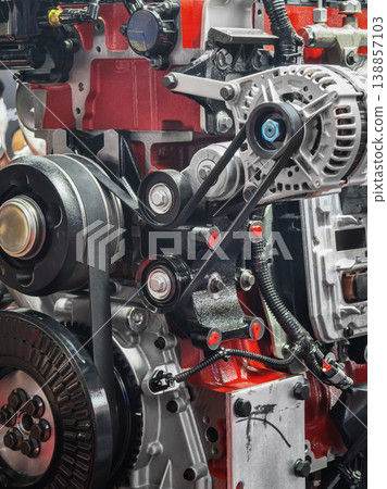 Engine components in a workshop during a mechanical repair session in the afternoon with focus on belts and pulleys 138857103