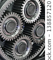 Close view of four metal gears in a mechanical system showing details of teeth and bearings during assembly process in a workshop 138857120