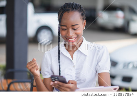 Young Black woman celebrating while looking at tablet on stairs. Good news, success, online learning, business progress, digital achievement and positive productivity concept. Young Black woman celebrating while looking at tablet on stairs. Good news, success, online learning, business progress, digital achievement and positive productivity concept. 138857884