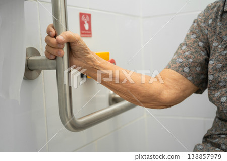 Asian elderly woman use toilet security support rail in bathroom. Asian elderly woman use toilet security support rail in bathroom. 138857979