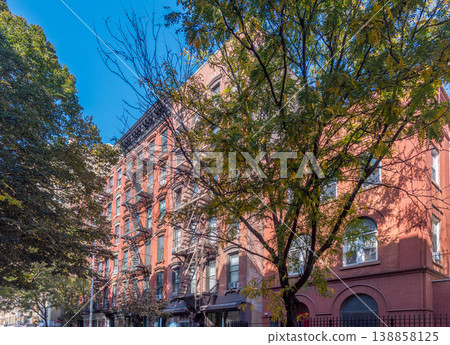 Green trees and orange buildings in a narrow street in Greenwich Village in Manhattan 138858125