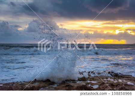 Dramatic Ocean Wave Splashing on Rock at Sunset with Yellow Light Dramatic Ocean Wave Splashing on Rock at Sunset with Yellow Light 138858966