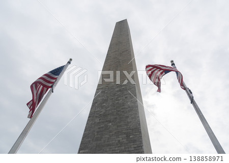 Low Angle View of Washington Monument Framed by Two American Flags under Gray Sky Low Angle View of Washington Monument Framed by Two American Flags under Gray Sky 138858971