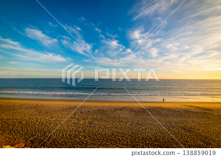 Two people walking on the beach at sunset 138859019