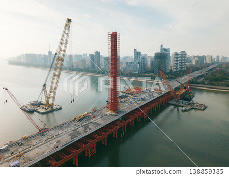 Aerial view of cranes and construction equipment are working to dismantle an old cable stayed bridge. Aerial view of cranes and construction equipment are working to dismantle an old cable stayed bridge. 138859385