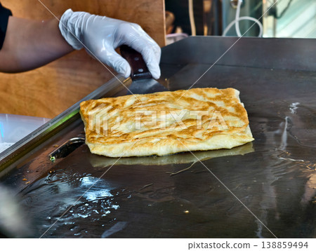 Crispy Flatbread Being Cooked on a Griddle in a Street Food Setting 138859494