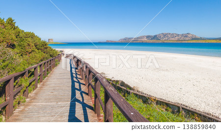 Wooden boardwalk to the beach in La Pelosa under a blue sky Wooden boardwalk to the beach in La Pelosa under a blue sky 138859840