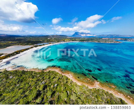 Aerial view of Cala Brandinchi beach surrounded by greenery under blue sky with white clouds 138859863