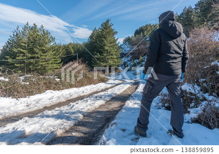 Man Seen from Behind Standing on Snowy Mountain Road Under Blue Sky Man Seen from Behind Standing on Snowy Mountain Road Under Blue Sky 138859895