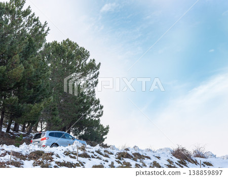 SUV on a Mountain Road Surrounded by Snow Under a Blue Sky with Clouds SUV on a Mountain Road Surrounded by Snow Under a Blue Sky with Clouds 138859897