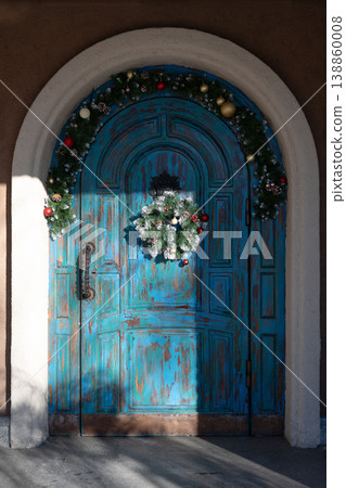 Old wooden door decorated with a Christmas wreath Old wooden door decorated with a Christmas wreath 138860008