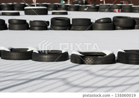 Racetrack fence . Old used tires on a kart racing track  . 138860019