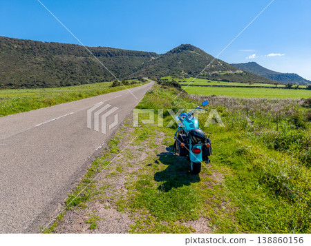 Turquoise Custom Motorcycle Parked on a Country Road with Hill in the Background Turquoise Custom Motorcycle Parked on a Country Road with Hill in the Background 138860156
