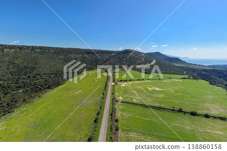 Aerial View of an Empty Country Road Leading to a Hill Under Blue Sky 138860158