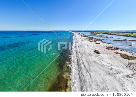 Aerial view of a white sand beach with blue water on a sunny day. Aerial view of a white sand beach with blue water on a sunny day. 138860164