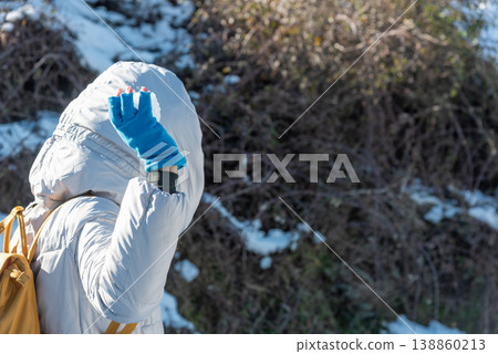 Close-Up of Woman in Winter Clothes Holding a Snowball Seen from Behind 138860213