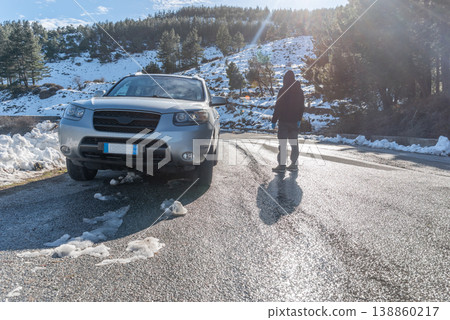 Man Standing Near SUV on Snowy Mountain Road Viewed from Behind 138860217