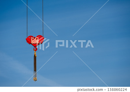 Close-up of a red crane hook against a clear blue sky  . Construction and industry concept . Copy space 138860224