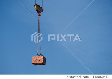 Crane Lifting Stack of Bricks Against Blue Sky .  Copy space 138860410
