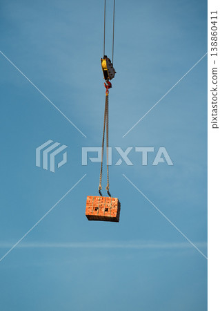 Crane Lifting Stack of Bricks Against Blue Sky . Vertical shot . Crane Lifting Stack of Bricks Against Blue Sky . Vertical shot . 138860411
